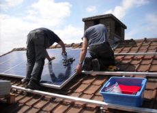 Men installing solar panels on a roof.