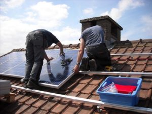 Men installing solar panels on a roof.